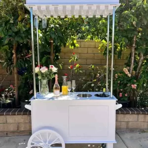 A white cart, available for party rental in Texas, with a bottle of wine on it.