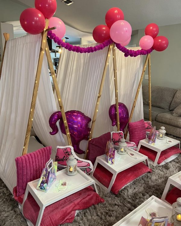 A pink and white teepee with balloon toppers.