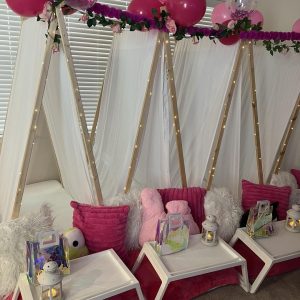 A pink teepee tent embellished with balloons and decorations.