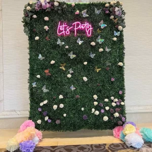 A green wall adorned with enchanting flowers and a sign that reads "life party.