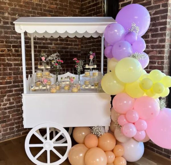 An elegant ice cream cart with balloons on it.
