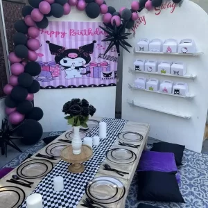 A table set up for a birthday party with black and pink balloons, available through our Texas party rental service.