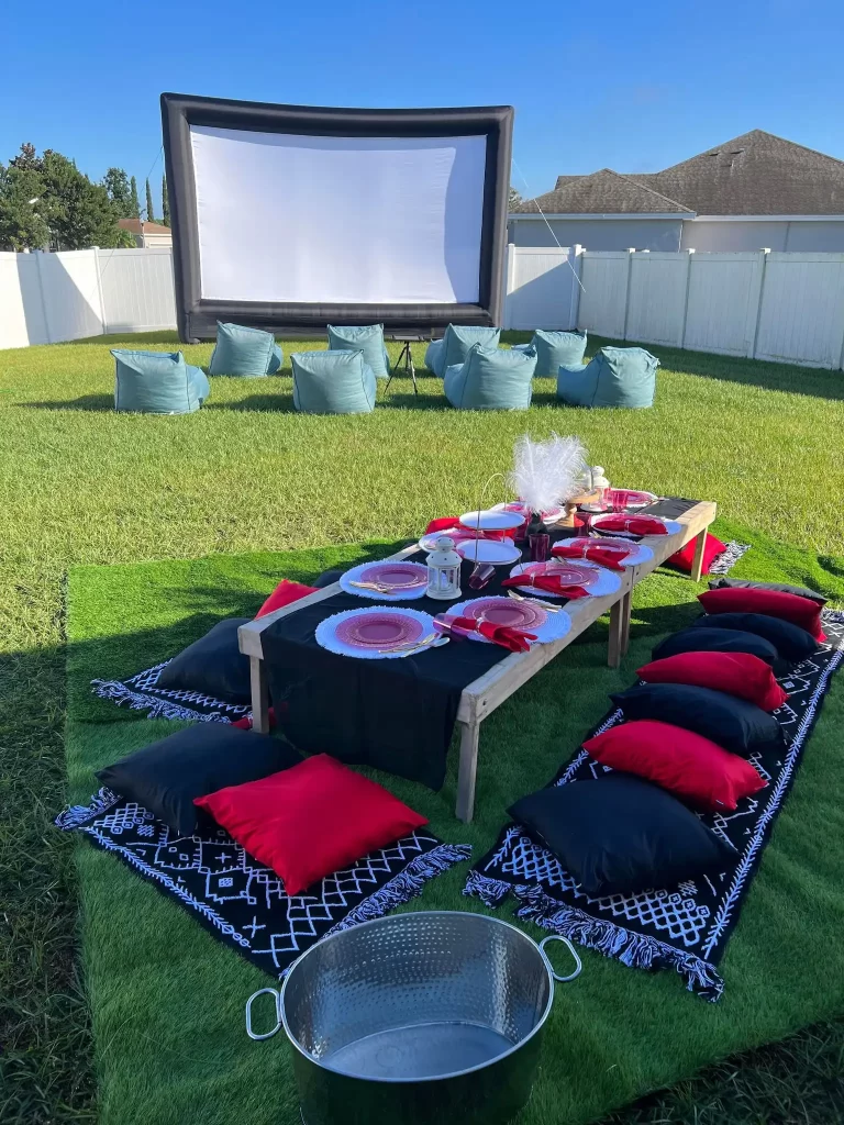 A backyard movie set up in Texas with pillows and a party rental movie screen.