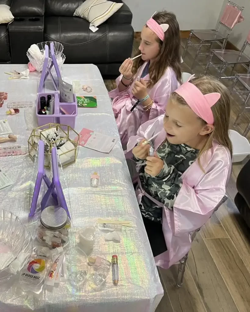 Two girls in pink robes sitting at a Texas party rental table.