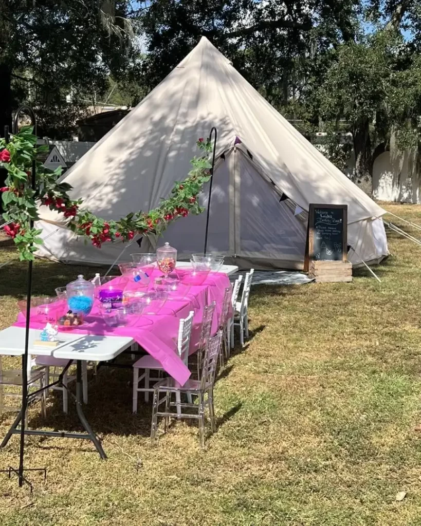 A pink party rental tent with a table and chairs in front of it.