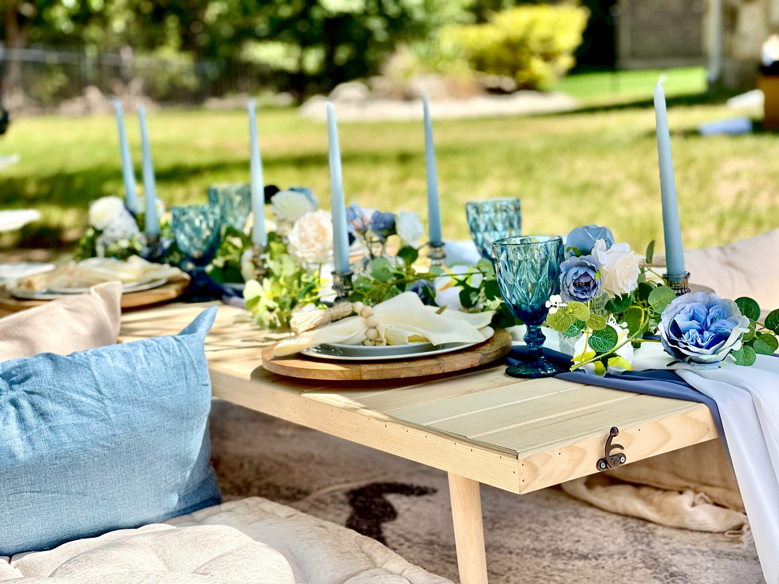 A blue and white picnic table set up in a grassy area, available through our Texas party rental service.