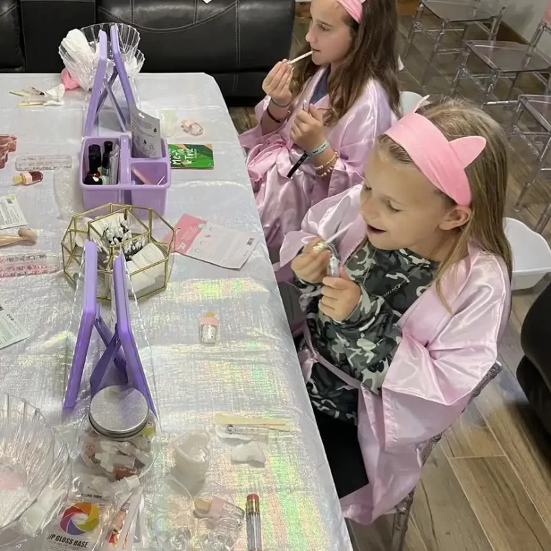 Two girls in pink robes sitting at a Texas party rental table.