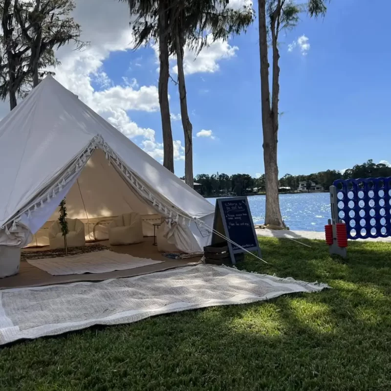 A white party rental tent set up in the grass next to a lake in Texas.