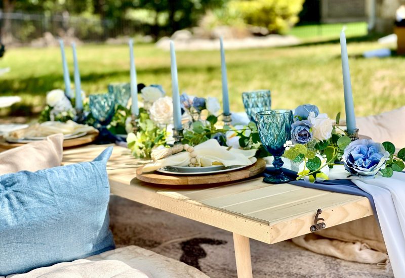 A blue and white picnic table set up in a grassy area, available through our Texas party rental service.