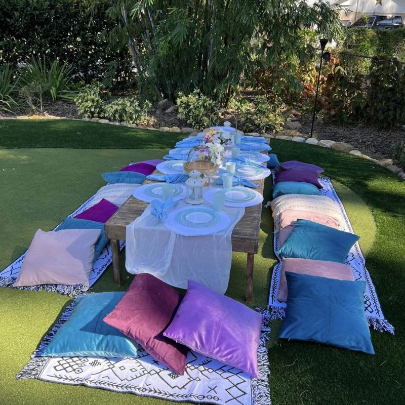 A table set up in a Texas backyard with pillows for a party rental.
