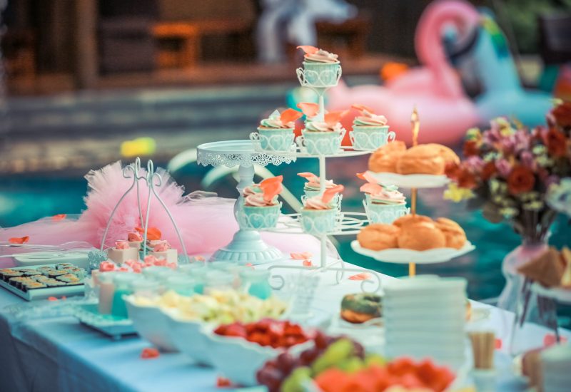 A dessert table with cupcakes and cupcakes on a table next to a pool at a Texas party rental.