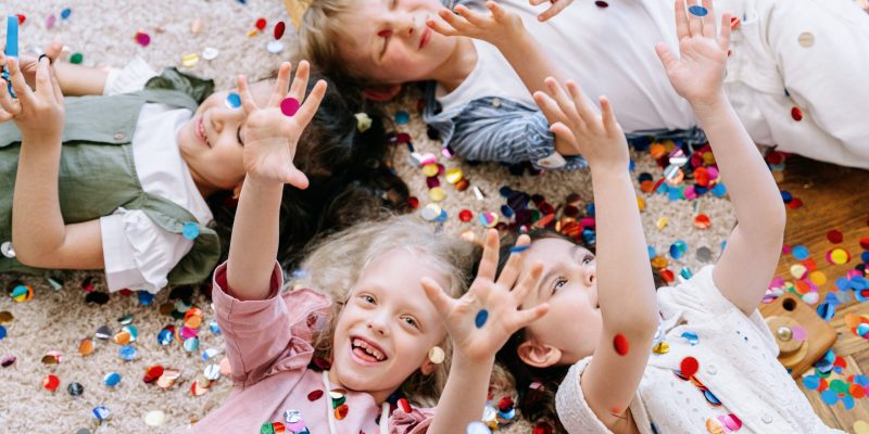 Children laying on the floor with confetti in their hands at a Texas party rental.