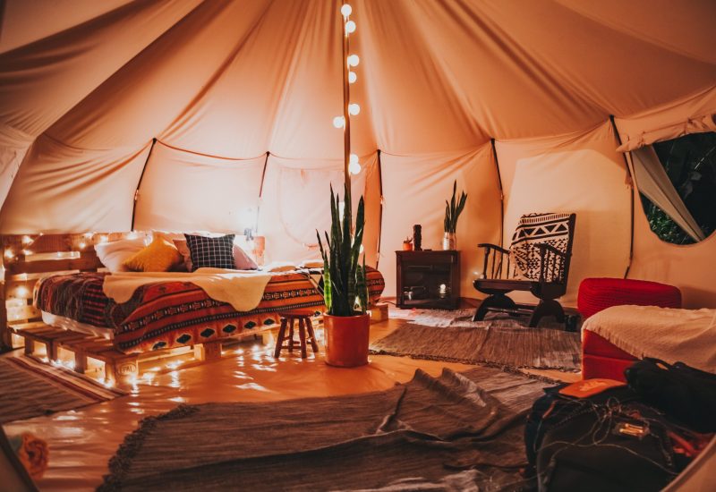 A room in a Texas tent with lights, a bed, and party rental amenities.