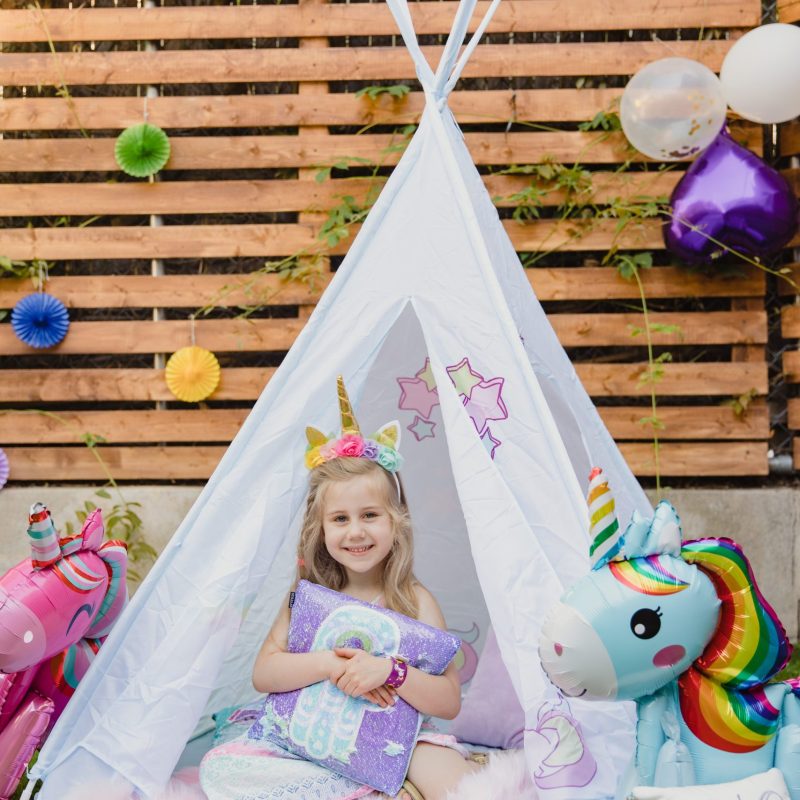 A girl sits in a teepee with unicorns and stuffed animals at a Texas party rental.
